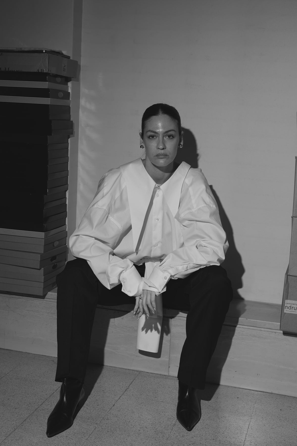 Ritratto in bianco e nero della fondatrice di All Hours, con camicia bianca e pantaloni neri.